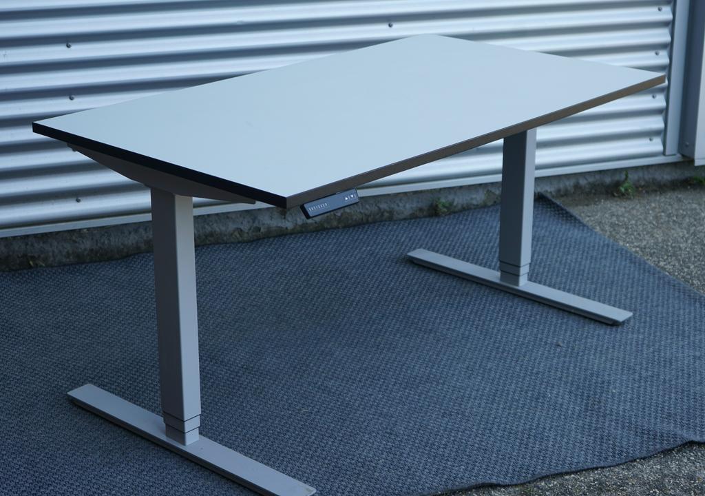 Dencon hæve-sænkebord 140x80 med hvid bordplade og gråt stel set fra skrå vinkel.